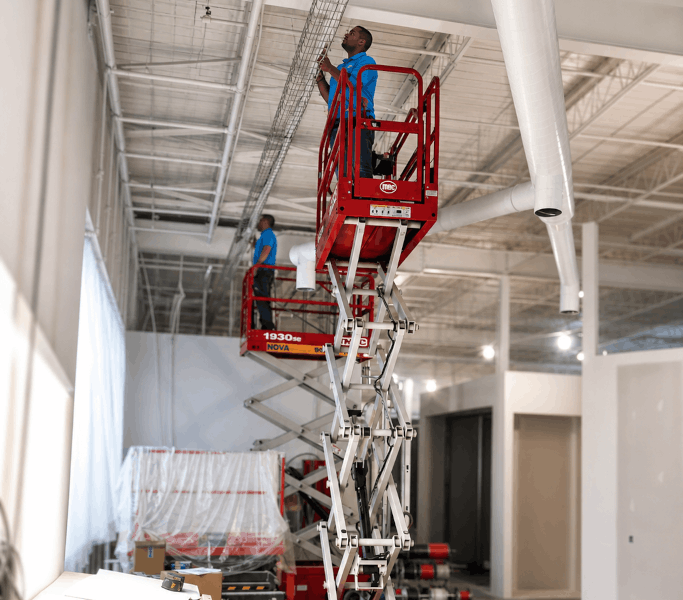 Two Techs Working on Scissor Lifts to Run Camera Cables